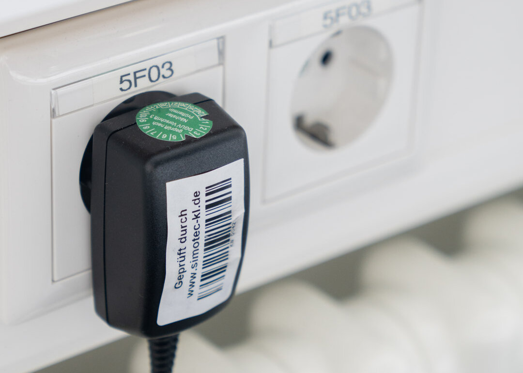 Stecker in der Steckdose mit Simotec Prüfplakette